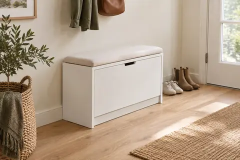 Banc à chaussures blanc avec assise rembourrée et rangement basculant dans une entrée lumineuse.