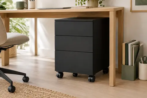Caisson de bureau noir mat à trois tiroirs sur roulettes, placé sous un bureau en chêne clair.